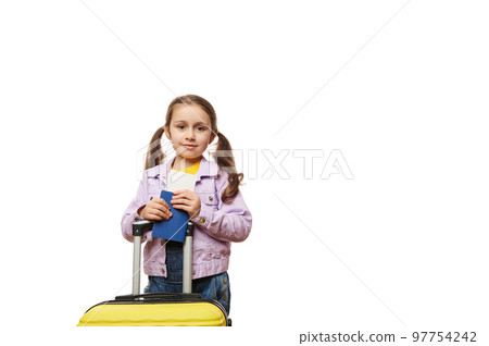 Beautiful 5 years old child, Caucasian lovely little traveler girl with yellow suitcase, going for summer vacation, holding boarding pass flight ticket, isolated on white background. Advertising space 97754242