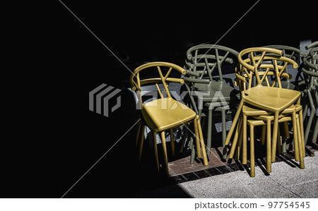 Detail of Stack of Dark green (Khaki color) and Yellow plastic chairs. 97754545