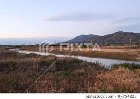 Sakuragawa River and Mount Hokyo and Mount Tsukuba under the winter sky, a tranquil landscape seen through the grass Sakuragawa River and Mount Hokyo and Mount Tsukuba under the winter sky, a tranquil landscape seen through the grass 97754825