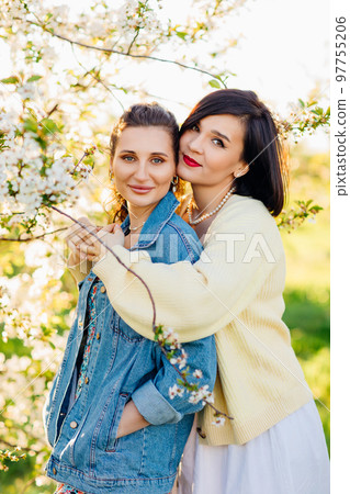 two attractive women hugging in a spring garden. two attractive women hugging in a spring garden. 97755206