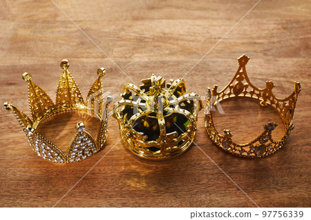 Happy Epiphany day. Three gold crowns on wooden background, symbol of Tres Reyes Magos, Three Wise Men.  97756339