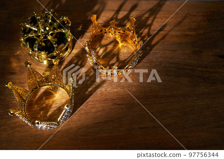 Happy Epiphany day. Three gold crowns on wooden background, symbol of Tres Reyes Magos, Three Wise Men.  97756344