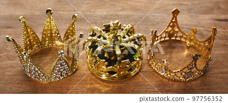 Happy Epiphany day. Three gold crowns on wooden background, symbol of Tres Reyes Magos, Three Wise Men.  97756352