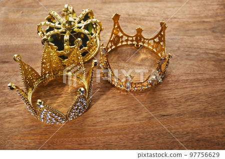 Happy Epiphany day. Three gold crowns on wooden background, symbol of Tres Reyes Magos, Three Wise Men.  97756629
