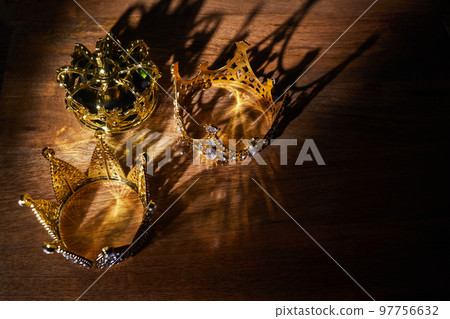 Happy Epiphany day. Three gold crowns on wooden background, symbol of Tres Reyes Magos, Three Wise Men.  97756632