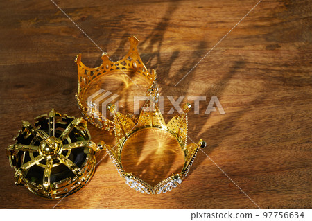 Happy Epiphany day. Three gold crowns on wooden background, symbol of Tres Reyes Magos, Three Wise Men.  97756634