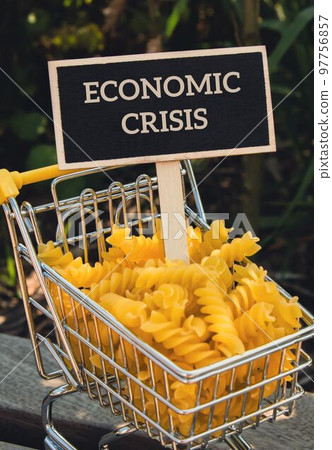 ECONOMIC CRISIS text on Blackboard label Shopping trolley cart Filled With Pasta on agriculture background. Food and groceries shopping price increase, Rising food cost food crisis inflation ECONOMIC CRISIS text on Blackboard label Shopping trolley cart Filled With Pasta on agriculture background. Food and groceries shopping price increase, Rising food cost food crisis inflation 97756857