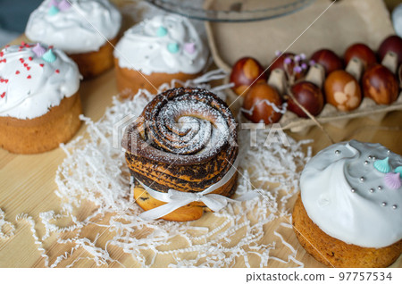 Easter cake kraffin with poppy seeds is on the table near the red eggs Easter cake kraffin with poppy seeds is on the table near the red eggs 97757534