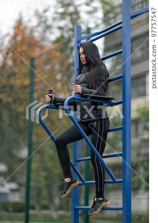 Long-haired slender brunette goes in for sports on a street sports ground Long-haired slender brunette goes in for sports on a street sports ground 97757547