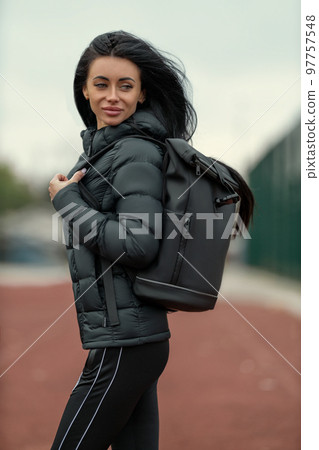 Portrait of beautiful young brunette woman outdoors in black sportswear Portrait of beautiful young brunette woman outdoors in black sportswear 97757548