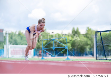 Young caucasian woman is engaged in jogging at the stadium outdoors. Young caucasian woman is engaged in jogging at the stadium outdoors. 97758971