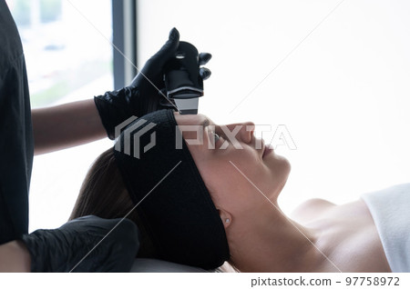 Woman on ultrasonic cleaning procedure. Hardware cosmetology.  97758972