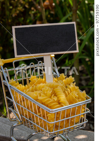 Empty mockup template Blackboard label against Shopping trolley cart Filled With Pasta on agriculture background. Copy space for your text. Food and groceries shopping price increase, Rising food cost Empty mockup template Blackboard label against Shopping trolley cart Filled With Pasta on agriculture background. Copy space for your text. Food and groceries shopping price increase, Rising food cost 97759390