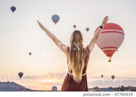 Tourist woman looking at hot air balloons in Cappadocia, Turkey. Happy Travel in Turkey concept. Woman on a mountain top enjoying wonderful view 97760939
