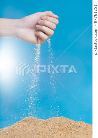 Hand releasing dropping sand. Fine Sand flowing pouring through fingers against blue background. Summer beach holiday vacation and time passing concept. Isolated high speed shutter Hand releasing dropping sand. Fine Sand flowing pouring through fingers against blue background. Summer beach holiday vacation and time passing concept. Isolated high speed shutter 97761251