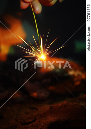 Hand-held sparkler in dusty state outdoors at night 97761386