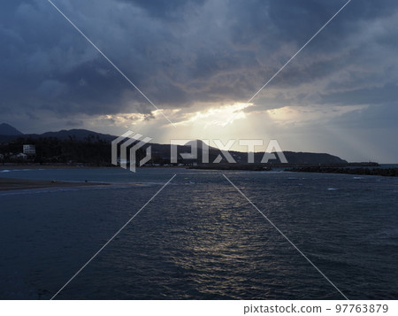 The Sea of Japan in winter when the sun shines through the cloudy sky at dusk 97763879