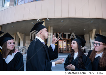 Happy students in graduate gown communicate in sign language. Happy students in graduate gown communicate in sign language. 97764467