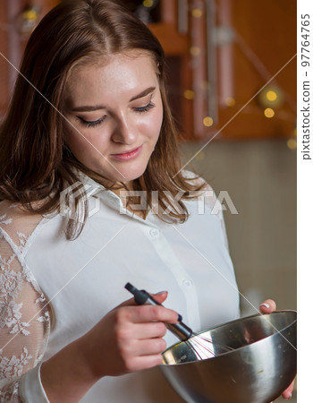 A girl prepares a cream for a festive Christmas cake in a kitchen decorated for Christmas A girl prepares a cream for a festive Christmas cake in a kitchen decorated for Christmas 97764765
