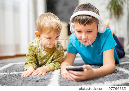 Two children watching smart phone, happy kids using smartphones together Two children watching smart phone, happy kids using smartphones together 97766885