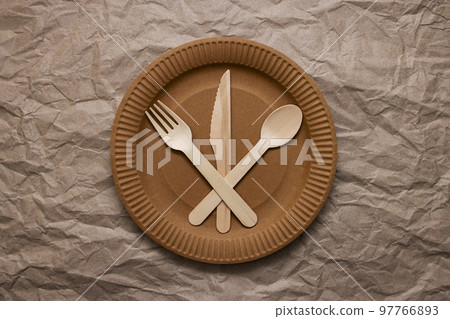Wooden fork, spoon and knife on cardboard plate on crumpled paper Wooden fork, spoon and knife on cardboard plate on crumpled paper 97766893