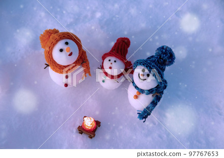 Snowman family looking up at the falling snow 97767653