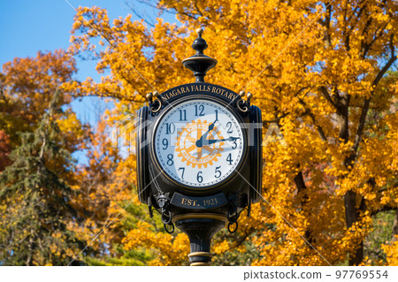 Niagara Falls City, Ontario, Canada - October 27 2022 : Skylon Tower, Niagara Falls Rotary Clock, autumn maple leaf over blue sky. Fall foliage. 97769554