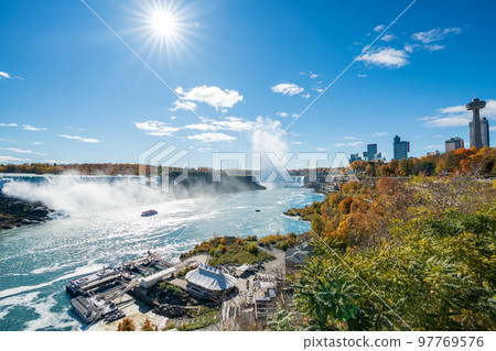 Niagara Falls American Falls and Horseshoe Falls in a sunny day in autumn foliage season. Niagara City Cruise Boat Tour. 97769576