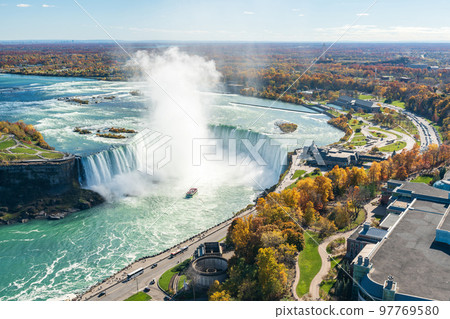 Overlooking the Niagara Falls Horseshoe Falls in a sunny day in autumn foliage season. Niagara Falls City, Ontario, Canada. 97769580