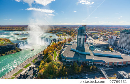 Niagara Falls City, Ontario, Canada - October 27 2022 : Niagara Falls Horseshoe Falls in autumn foliage season. Niagara Falls City downtown horizon. Hotels and Casino Resort. 97769581