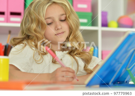 little girl studying at home at the table 97770963
