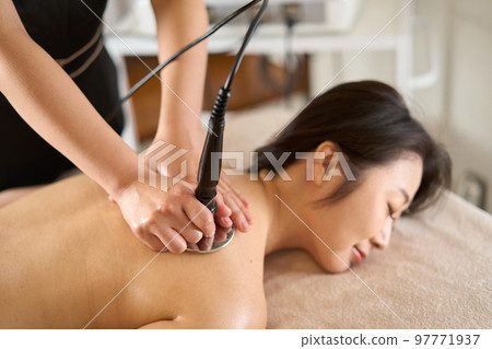 A woman undergoing treatment with a cavitation machine 97771937