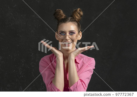 Happy wondering young woman with blue pink shadows on black background. Portrait of girl in big glasses 97772367