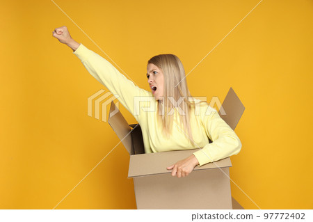 Concept of delivery and gift, young woman in box on yellow background Concept of delivery and gift, young woman in box on yellow background 97772402