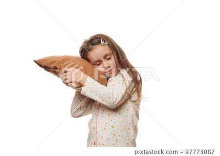 Isolated portrait on white background of a charming adorable child, lovely sleepy little girl in soft stylish pajamas, falling asleep, putting her head on a comfortable pillow. Copy advertising space Isolated portrait on white background of a charming adorable child, lovely sleepy little girl in soft stylish pajamas, falling asleep, putting her head on a comfortable pillow. Copy advertising space 97773087