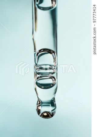 A drop of cosmetic oil falls from the pipette 97773414
