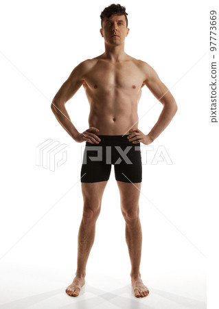 Front view. Portrait of mature handsome man with muscular body posing shirtless in black boxers over white studio background. Men's health and beauty Front view. Portrait of mature handsome man with muscular body posing shirtless in black boxers over white studio background. Men's health and beauty 97773669