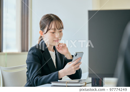 年輕女子在她的辦公桌前打電話 97774249
