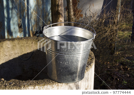 Rural well with a filled bucket of water 97774444