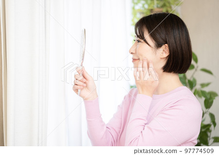 A woman smiling with a hand mirror A woman smiling with a hand mirror 97774509