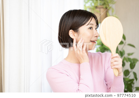 A woman smiling with a hand mirror A woman smiling with a hand mirror 97774510
