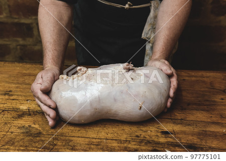 Hands making homemade head cheese, Patagonia, Argentina 97775101