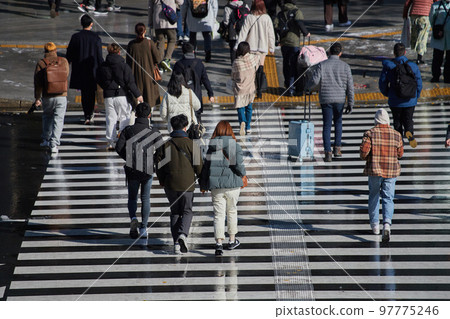 Figures of people walking on a pedestrian crossing in the city at the end of the year 97775246