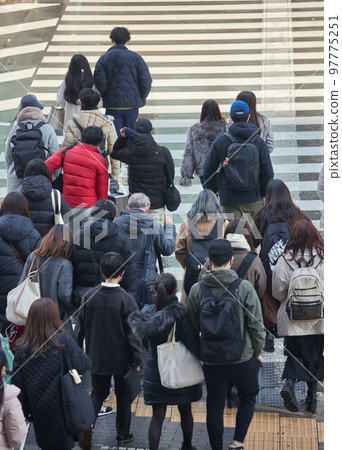 Figures of people walking on a pedestrian crossing in the city at the end of the year 97775251