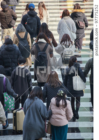 Figures of people walking on a pedestrian crossing in the city at the end of the year 97775252
