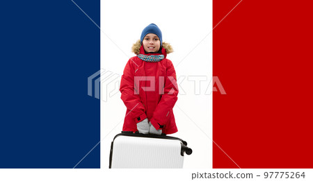 Handsome European teenage boy wearing blue knitted woolen hat and red down jacket, carrying a white suitcase over France flag background. Travel Journey Holidays concept Handsome European teenage boy wearing blue knitted woolen hat and red down jacket, carrying a white suitcase over France flag background. Travel Journey Holidays concept 97775264