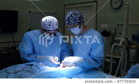 A team of surgeons perform facial nerve repair surgery. Group of professional surgeons and nurses in uniform performing surgery using medical instruments in operating room 97776920