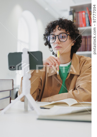 woman watches webinar from phone in office, coworking or library. work and study online 97777094