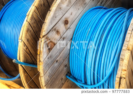 New blue power cable is wound on wooden coil. Background. Cable for laying underground.. 97777883