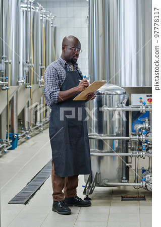 African American engineer controling the production of raw materials and making notes in document African American engineer controling the production of raw materials and making notes in document 97778117